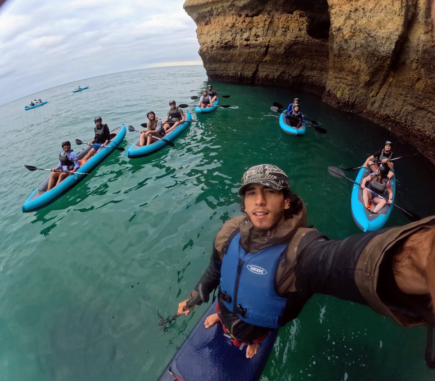GoPro photo of kayak guide Bruno with the group on turquoise water below the cliffs