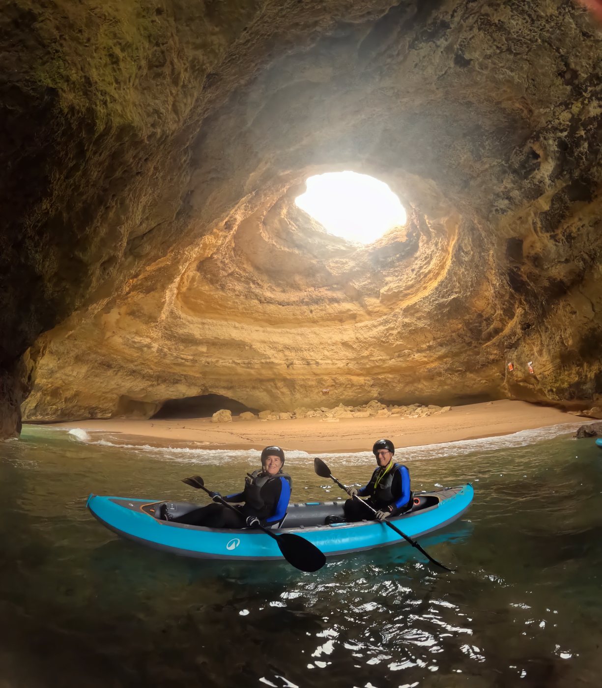 Ben and Kathy kayaking inside the Benagil cave with light streaming from the oculus
