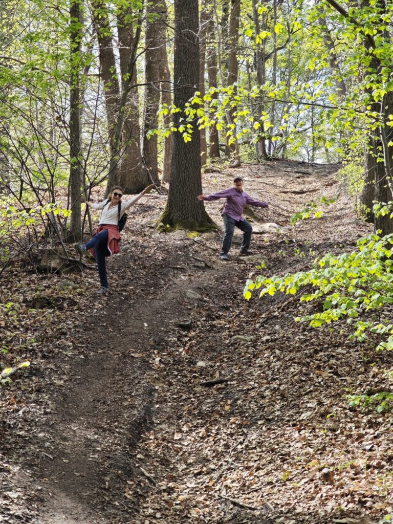 Two people playfully posing on a forest trail surrounded by early spring trees