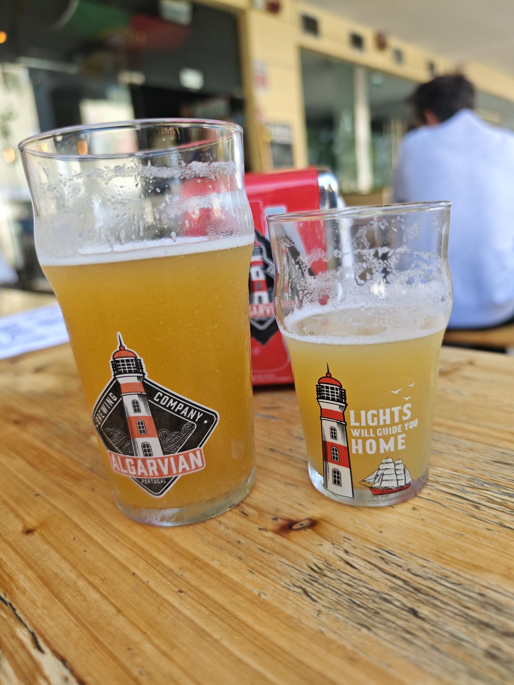 Two glasses of Algarvian Brewing Company beer on a wooden table