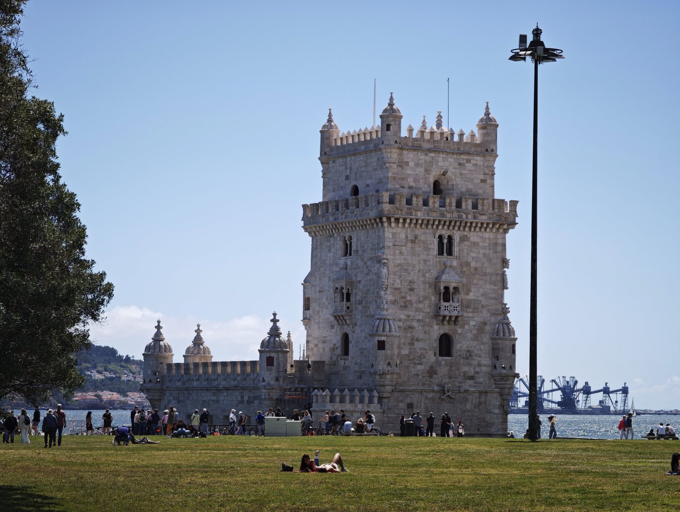 Belém Tower on a sunny day with tourists on the lawn