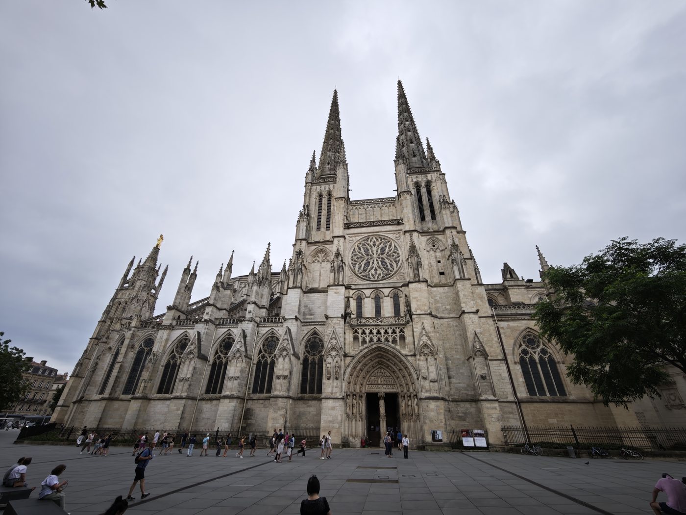 The Gothic facade of the Cathedrale Saint-Andre de Bordeaux with twin spires under an overcast sky