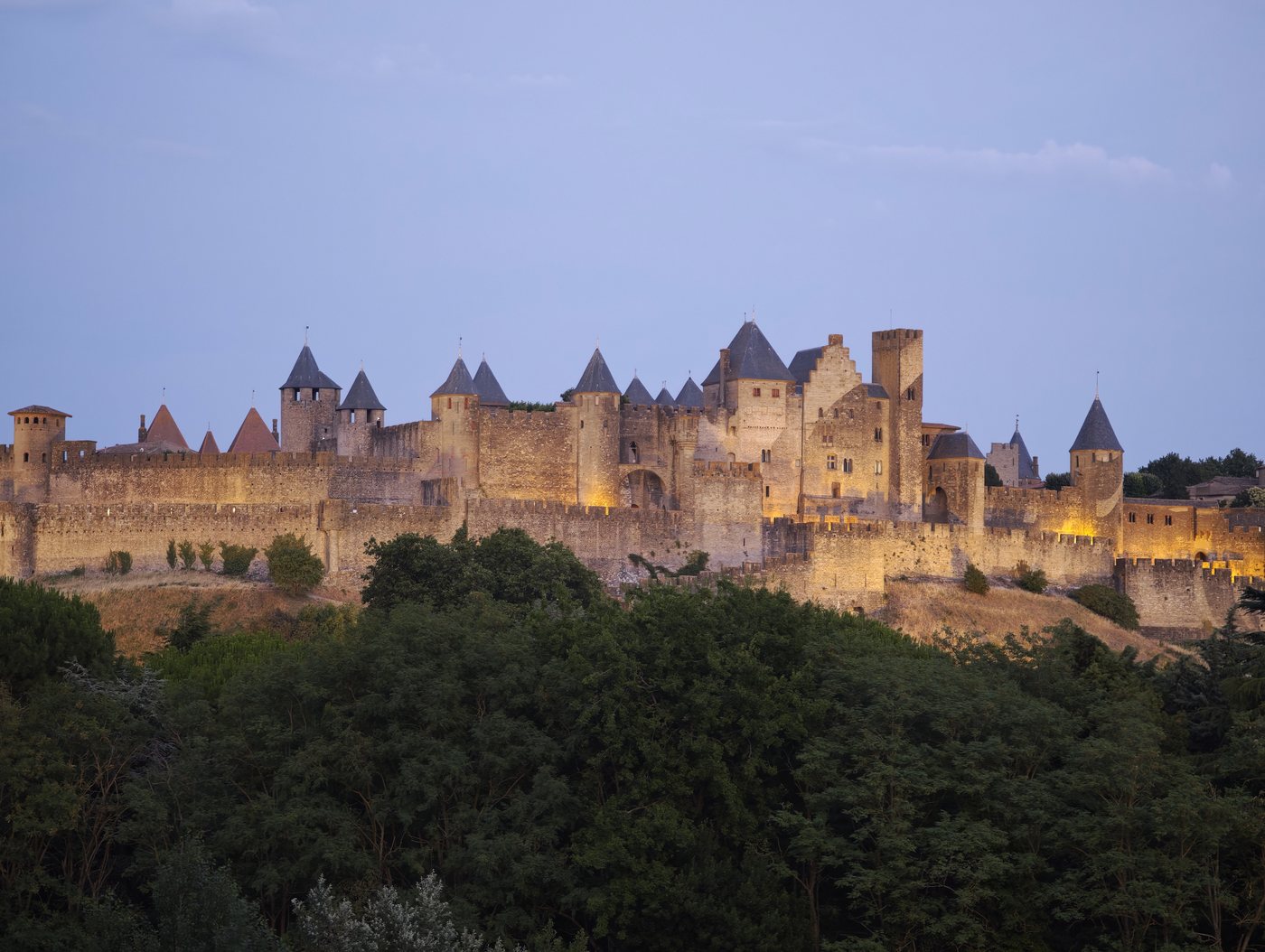 The Cite de Carcassonne lit up at dusk, its medieval towers and walls glowing amber